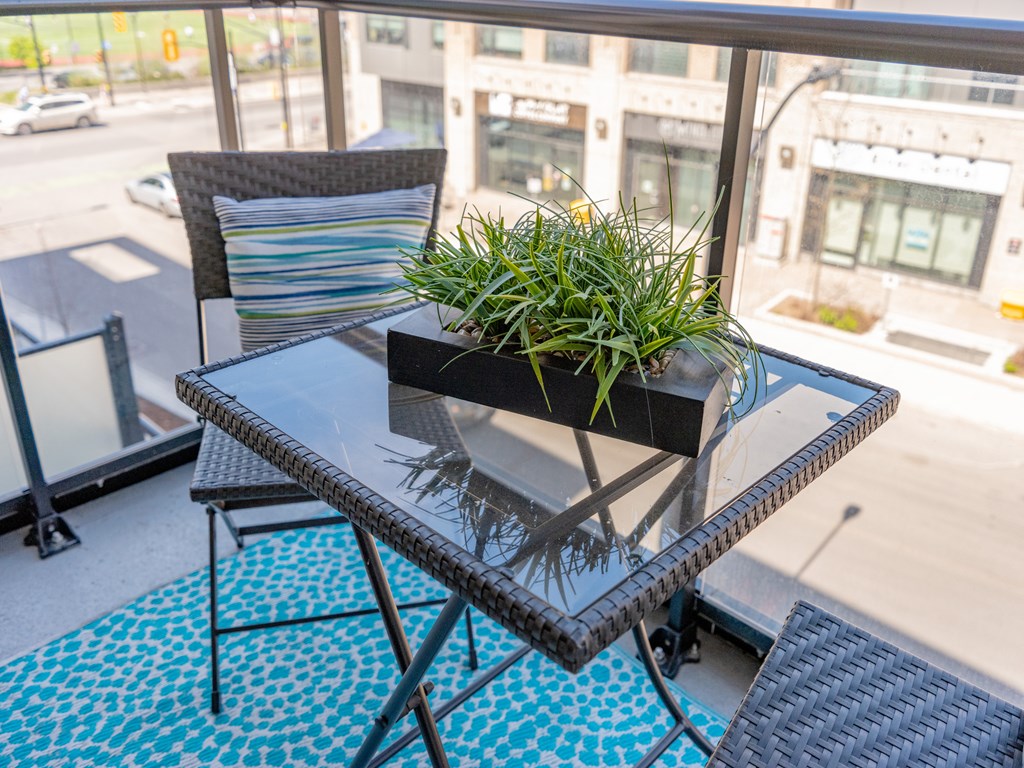 A table with a potted plant on it sits on a balcony.
