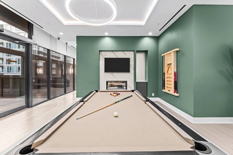 A pool table in a room with green walls and a television mounted on the wall.
