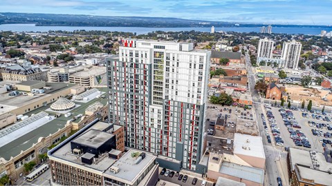 A tall building with a red and white logo on the top stands out in a cityscape.
