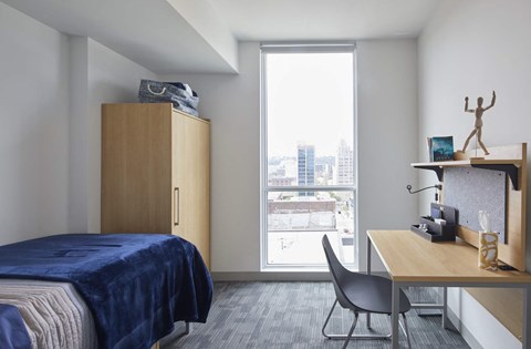 A bedroom with a bed, desk, and chair.