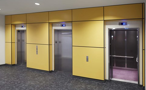 A row of elevators with yellow doors and silver doors.