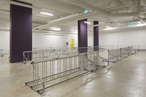 A long row of metal barricades are lined up in a large empty room.