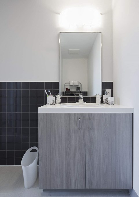 A bathroom with a grey cabinet and a mirror above it.