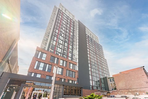 A modern building with a glass facade stands tall against a partly cloudy sky.