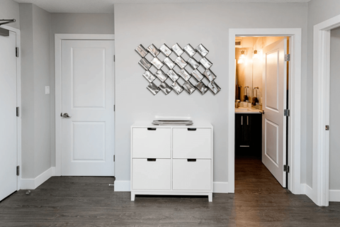 A white cabinet with a wall art above it.