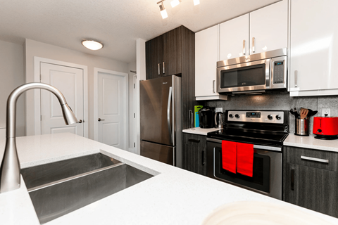 A modern kitchen with a stainless steel sink and refrigerator.