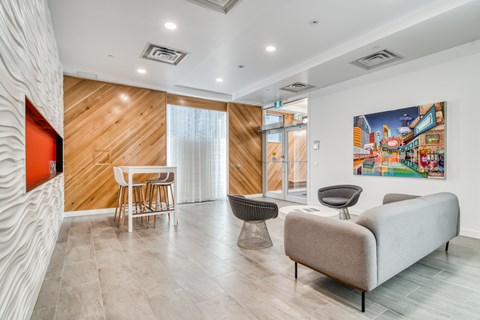 A living room with a grey sofa, a wooden wall, and a painting on the wall.