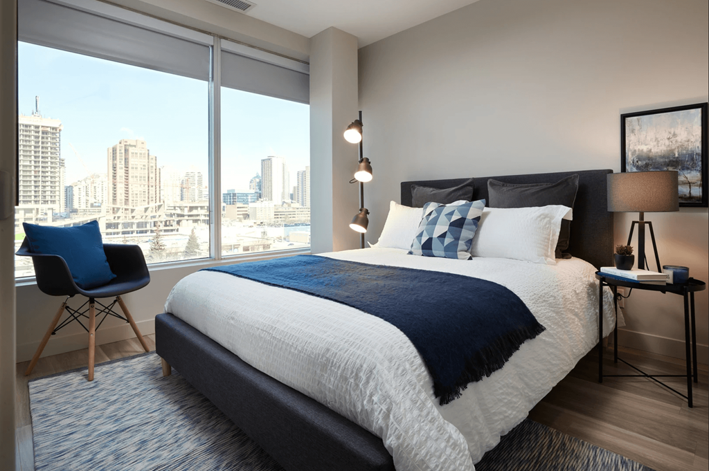 A bedroom with a large bed and a chair by the window.