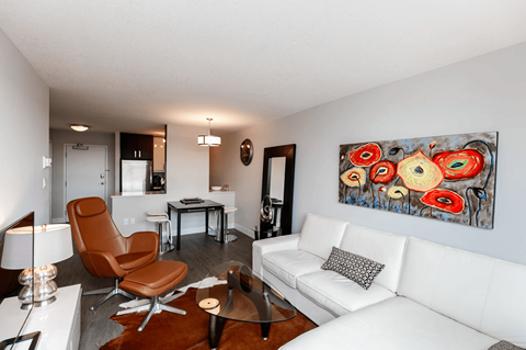 A living room with a white couch and a painting on the wall.