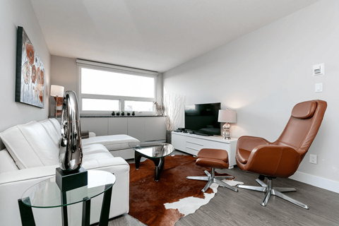 A living room with a white couch, a brown leather chair, and a glass coffee table.
