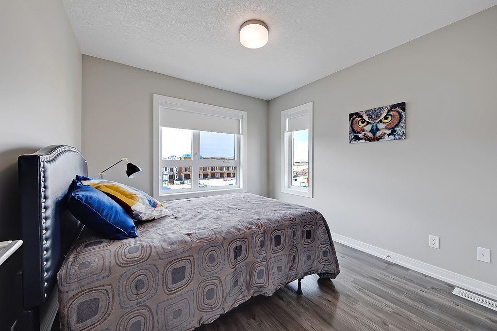A bedroom with a bed, a window, and a picture of an owl on the wall.