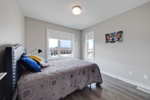 A bedroom with a bed, a window, and a picture of an owl on the wall.