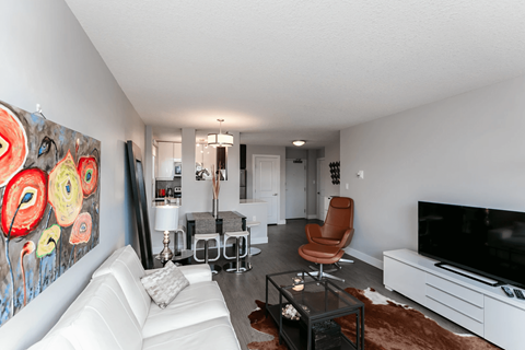 A living room with a white couch, a black coffee table, and a large painting on the wall.