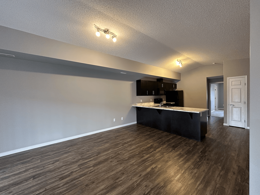 A room with a black counter and wooden floors.