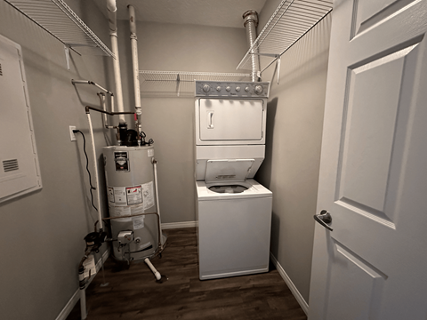 A small, white bathroom with a toilet and a water heater.
