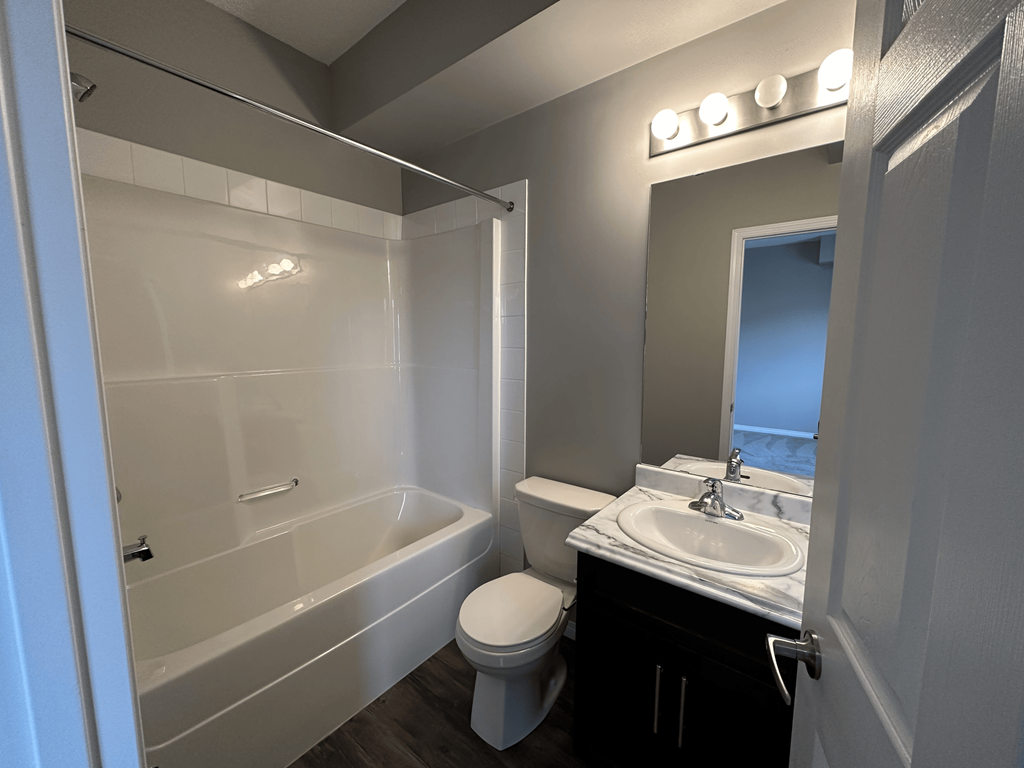 A bathroom with a white tub, toilet, and sink.