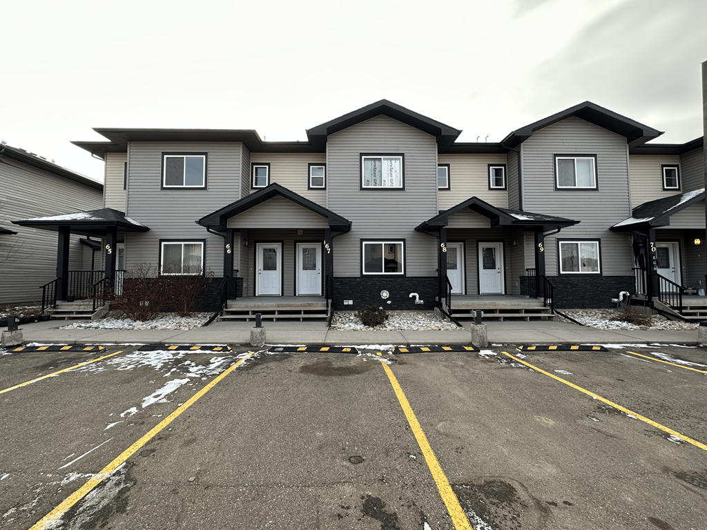 A row of houses with a parking lot in front.