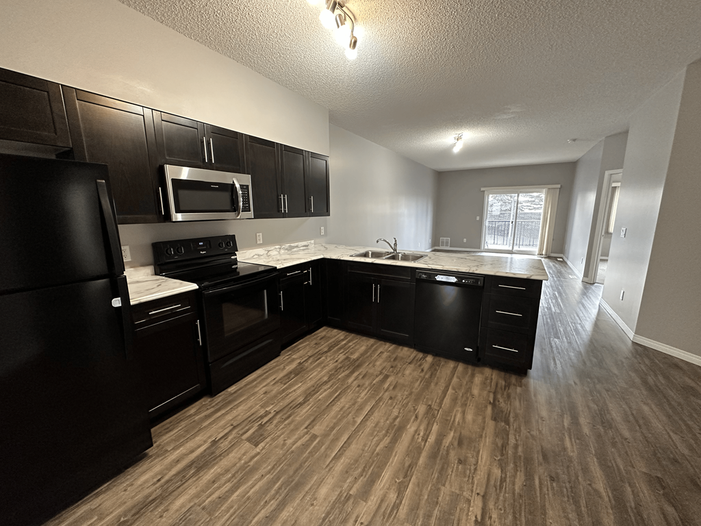 A kitchen with black cabinets and a black refrigerator.