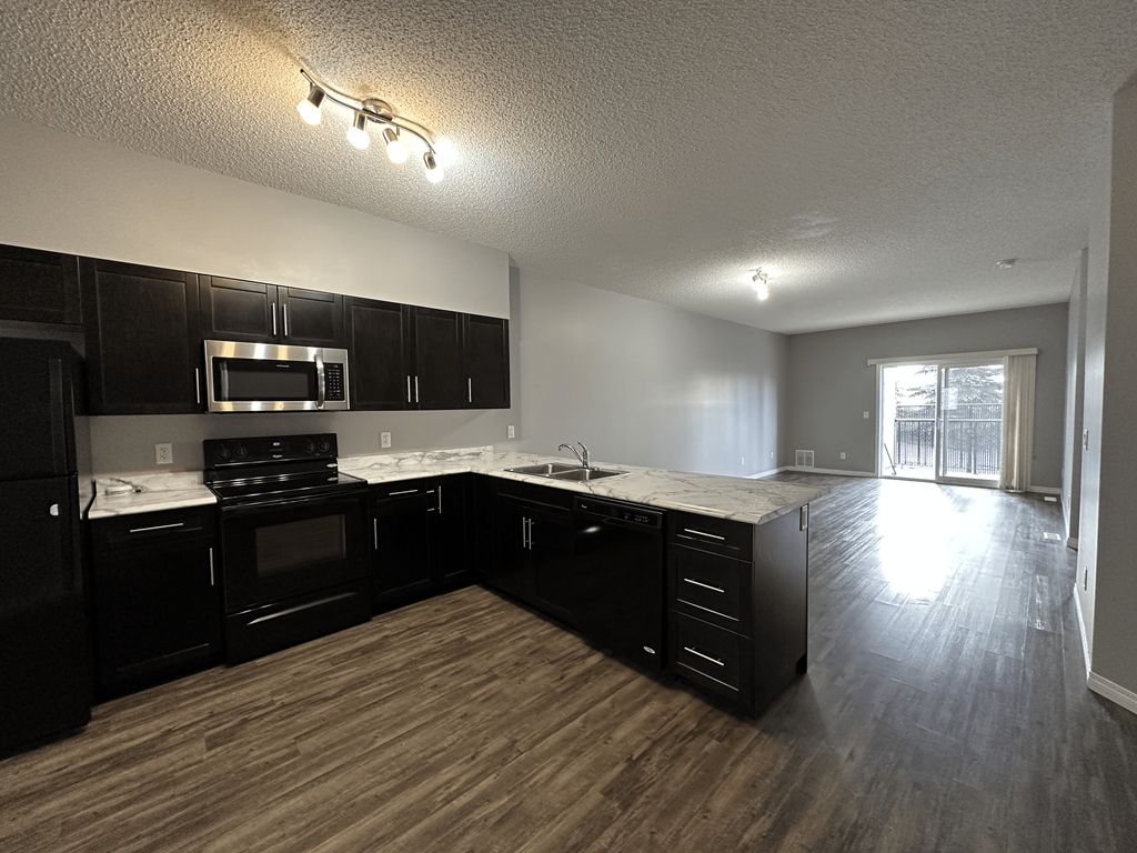 A kitchen with black cabinets and a stainless steel oven.