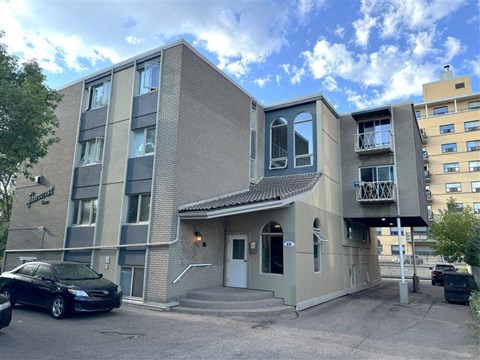 A modern two-story building with a parking lot in front.