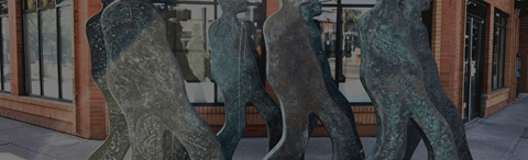 A group of four bronze statues of people stand in a row.