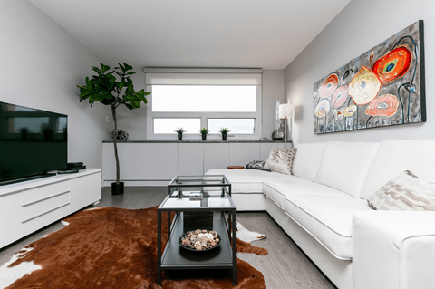 A living room with a white couch, a brown rug, and a painting on the wall.