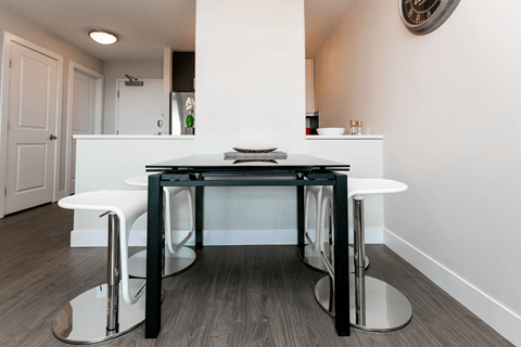 A modern kitchen with a white counter and black stools.