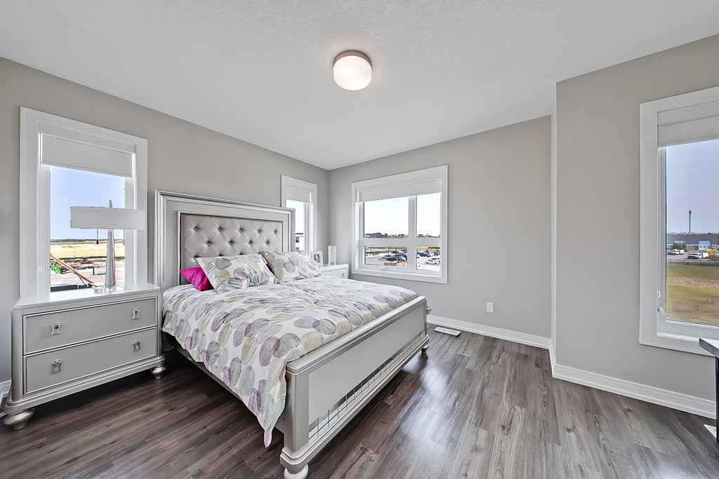 A bedroom with a large bed, dresser, and a window overlooking a field.