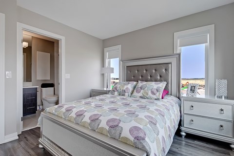 A bedroom with a large bed, a dresser, and a window.