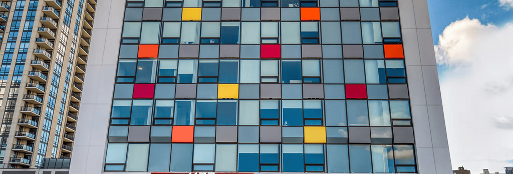 A tall building with a blue sky and clouds in the background.