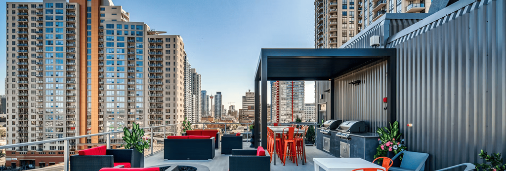 A rooftop patio with red seating and a black grill.