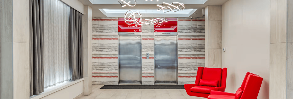 Two red chairs are placed in front of a wall with a striped pattern.