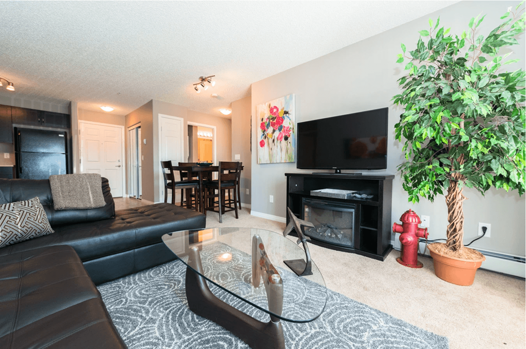 A living room with a black couch and a glass coffee table.