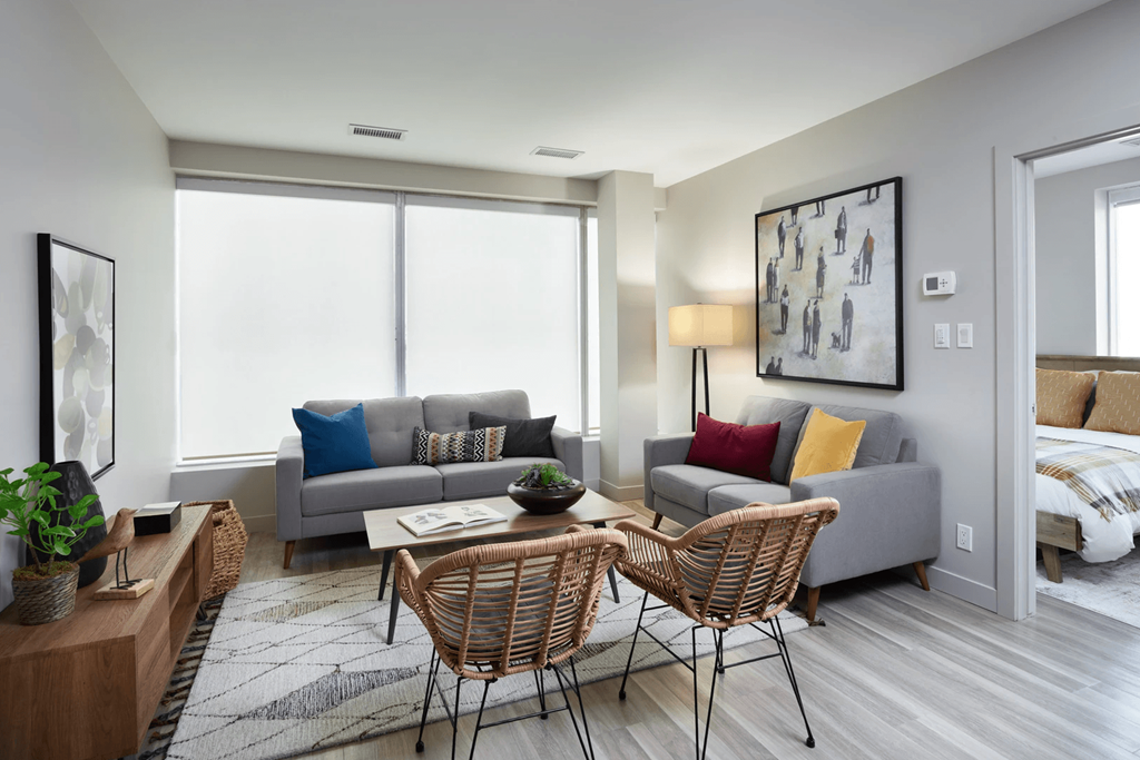 A living room with a grey couch, a wooden table, and a painting on the wall.