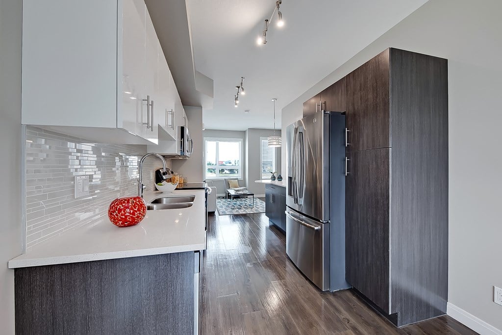 A modern kitchen with a refrigerator, sink, and cabinets.