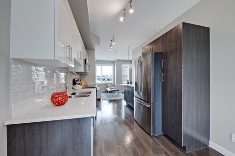 A modern kitchen with a refrigerator, sink, and cabinets.