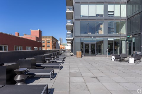 A modern building with a glass facade is the centerpiece of a spacious, clean courtyard.