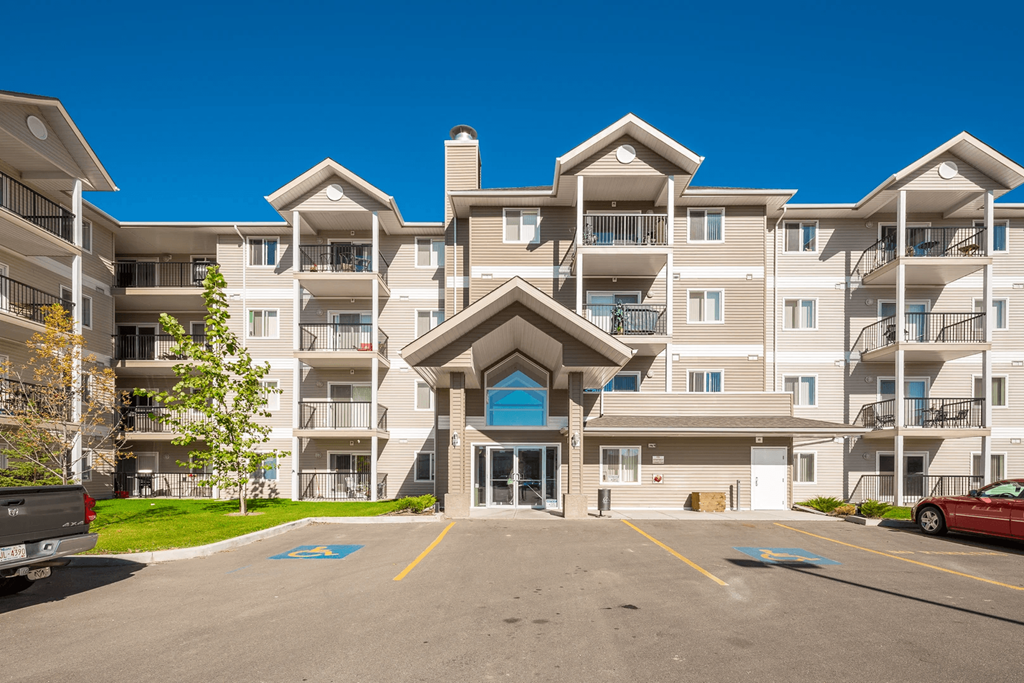 A large apartment complex with a parking lot in front.