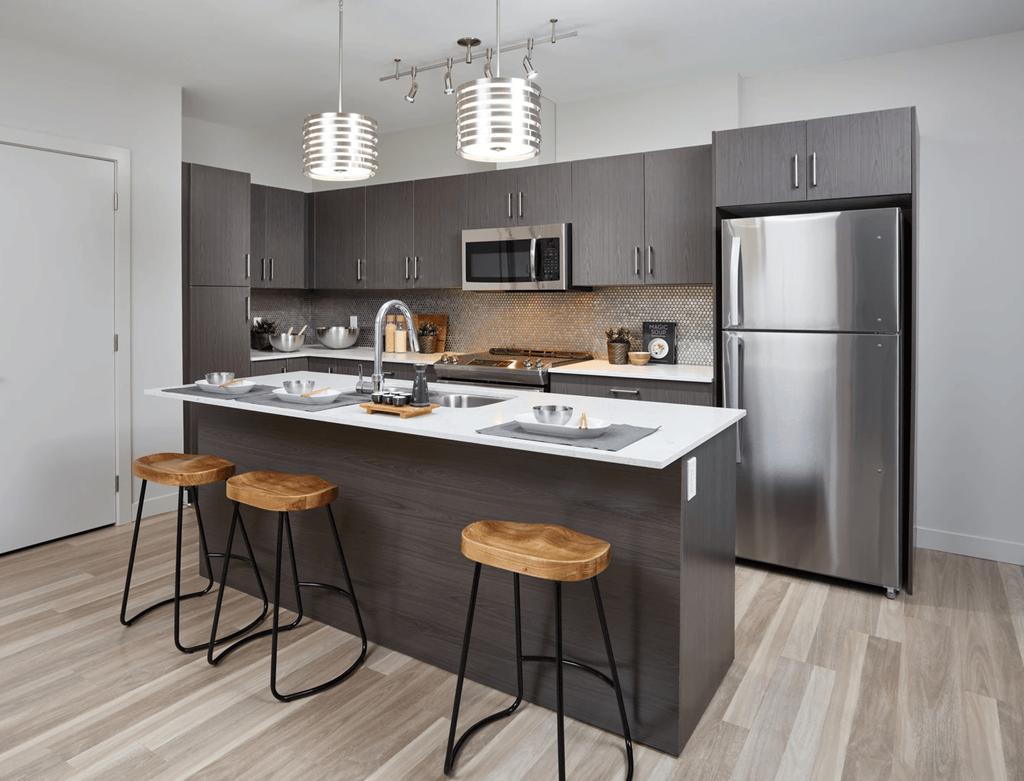 A modern kitchen with a stainless steel refrigerator and wooden bar stools.