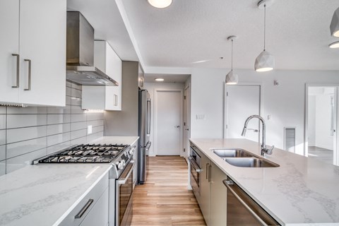 A modern kitchen with white cabinets and a marble countertop.