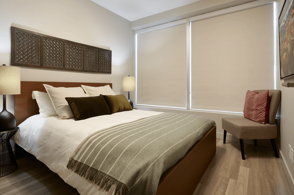 A bedroom with a bed, a chair, and a lamp.