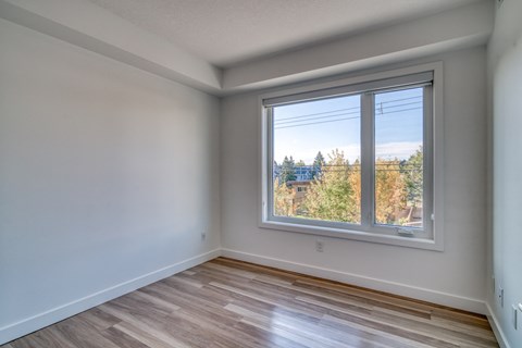 A room with a window showing a view of trees and a house.