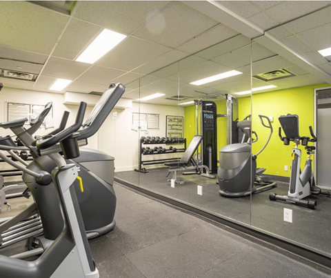 A gym with a variety of exercise equipment including treadmills, stationary bikes, and weight machines.