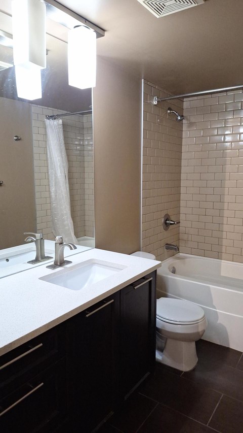 A bathroom with a white sink, black cabinetry, and a white toilet.