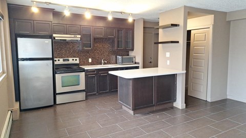 A kitchen with a refrigerator, oven, and sink.