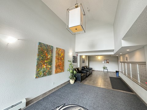 A hallway with a grey carpet and a black sofa.