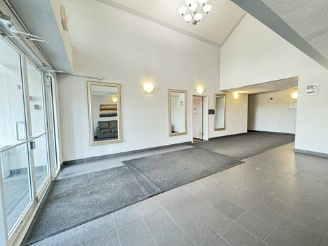 A spacious hallway with grey tiled floors and white walls.