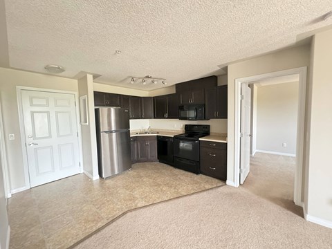 A kitchen with black cabinets and a stainless steel refrigerator.
