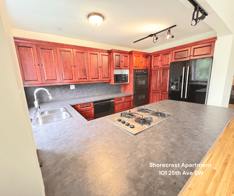 A kitchen with red cabinets and a stove top oven.