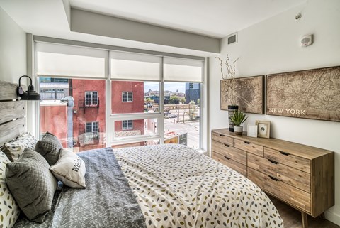 A bedroom with a large bed and a wooden dresser.